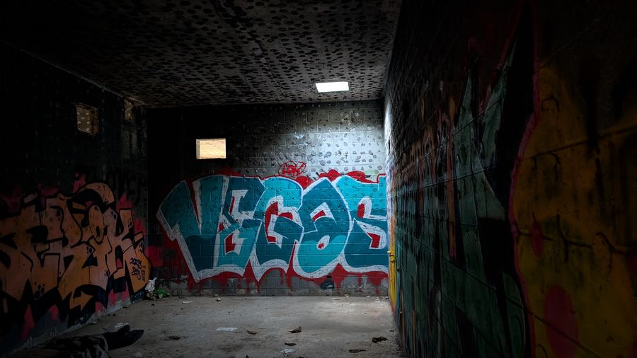 Atmospheric corridor with Vegas graffiti lettering glowing under a single light